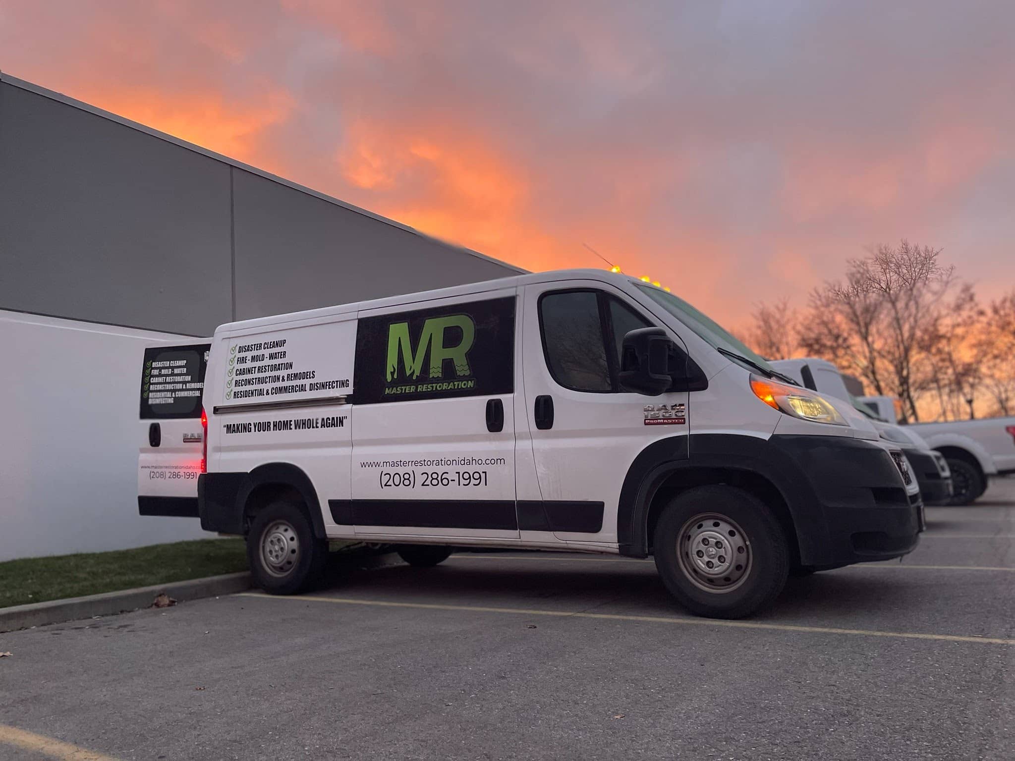 A white van with "Master Restoration" and contact details parked by a building at sunset.